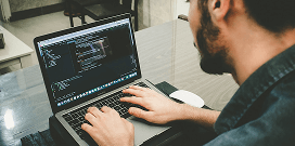 A worker uses automated storage software on his laptop to ensure all warehouse inventory is secure and accounted for