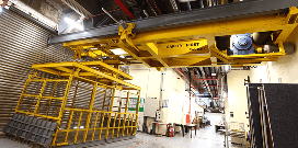 A yellow crane with a worker cage in a warehouse facility
