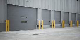 A row of warehouse docking bay doors protected by yellow bollards