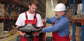 A worker in hard hat trains another worker on lift equipment